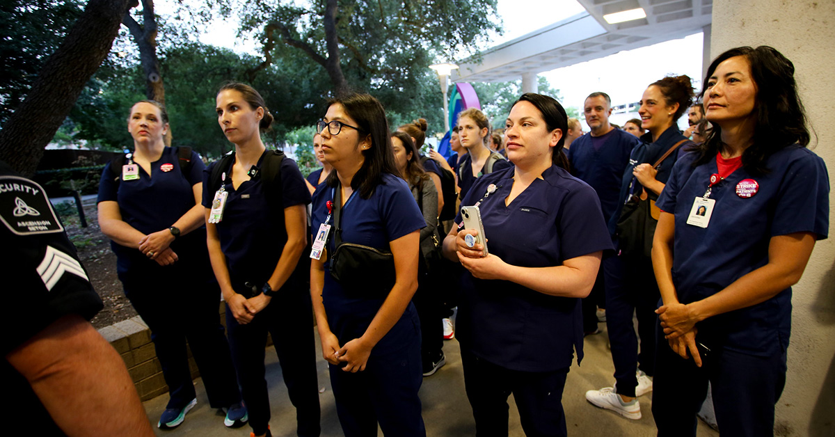 Group of Seton nurses stands outside hospital facing down security not allowing them to enter