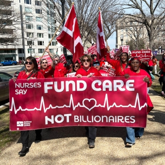 Nurses marching, holding banner "Fund Care Not Billionaires"