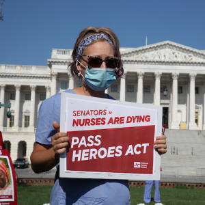 Nurse holds sign "Pass the HEROES Act" outside U.S. Senate