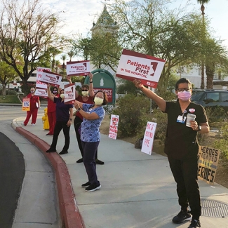 Nurses outside hospital hold signs "Patients First"