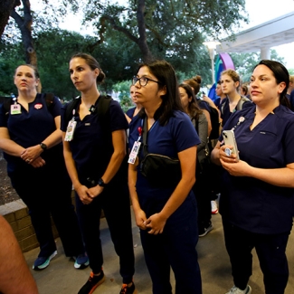 Group of Seton nurses stands outside hospital facing down security not allowing them to enter