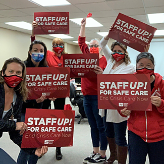Watsonville nurses holding signs "Staff UP for safe care. End Crisis Care Now"