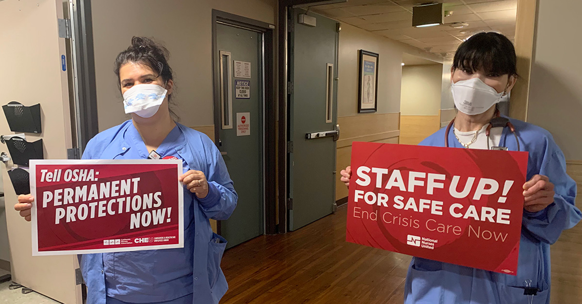 Two nurses inside hospital hold signs calling for permanent ETS and safe staffing