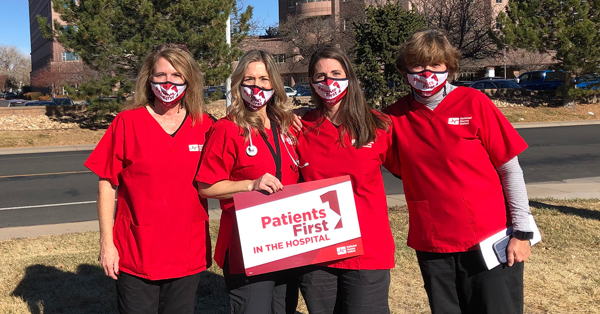 Group of four nurses outside Longmont Hospital hold sign "Patients First"