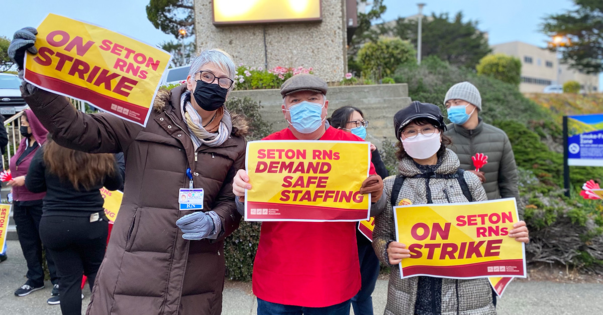Three nurses outside Seton Hospital hold signs "Seton RNs On Stirke!"