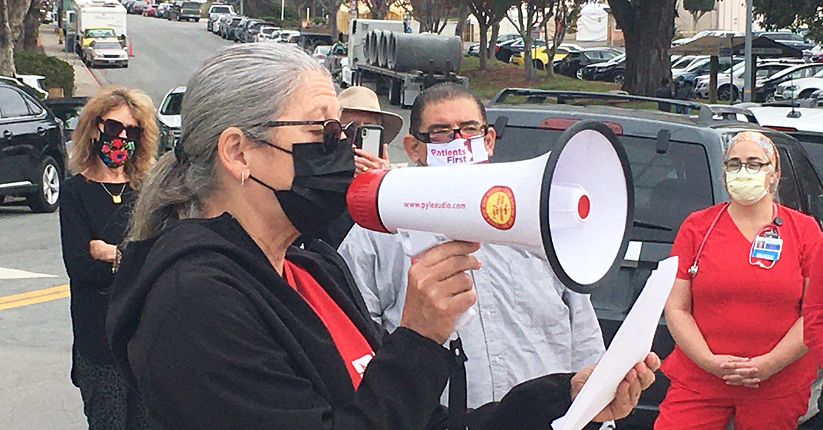 Nurse in front of crowd speaking into megaphone