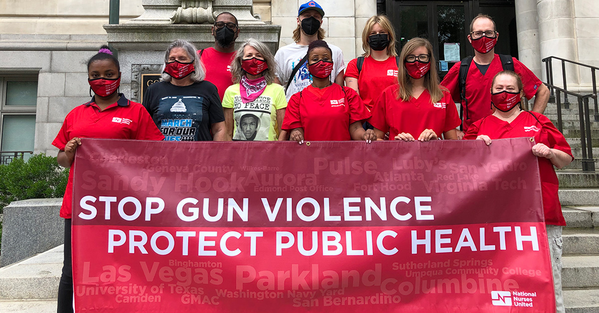 Group of nurses and family hold sign "Stop Gun Violence: Protect Public Health"