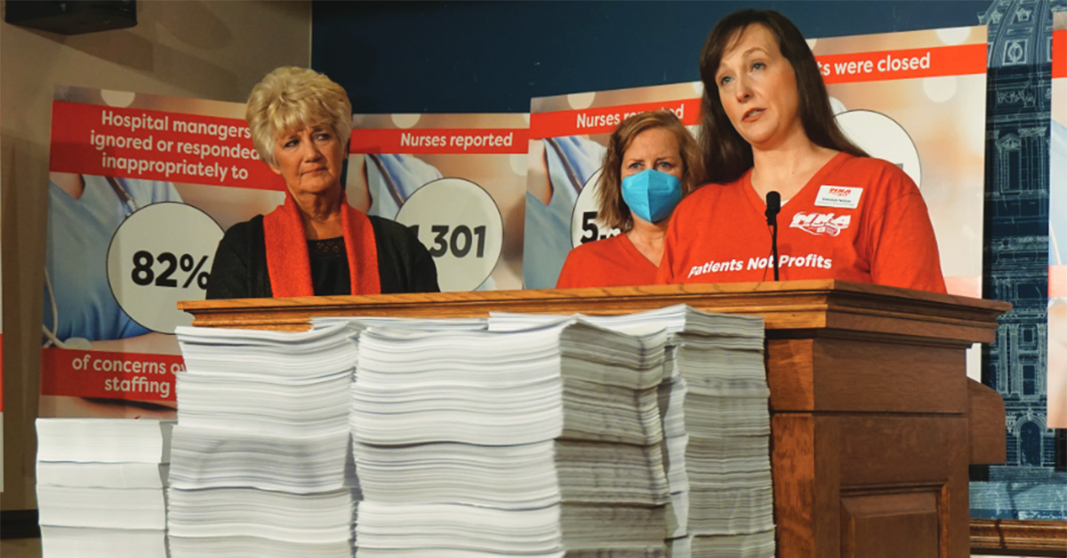 Group of three nurses standing at podium with stacks of paper report