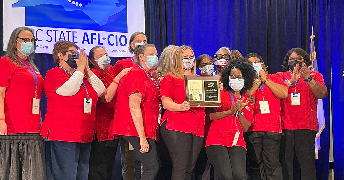 Large group of nurses accepting award on stage.