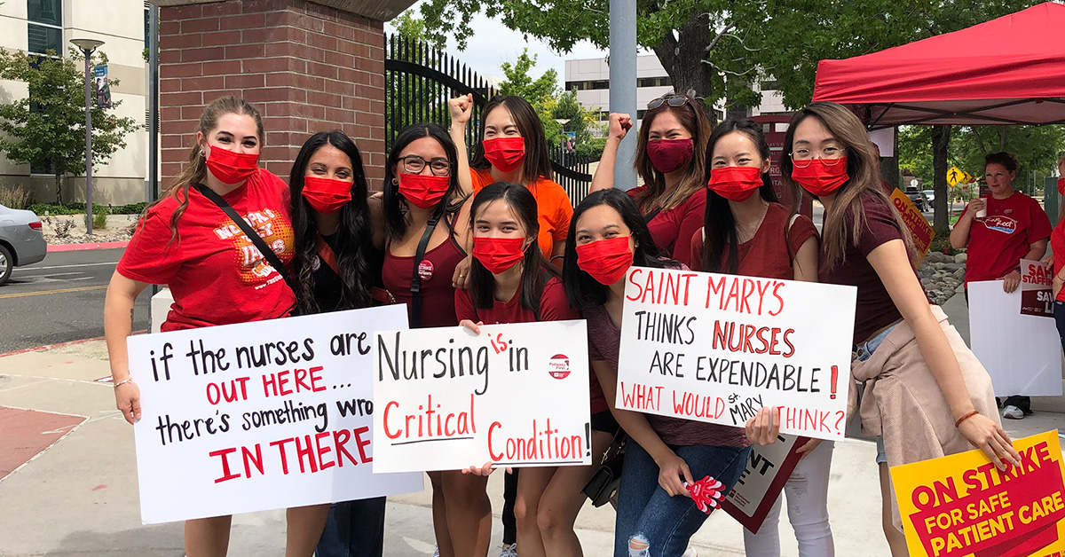 Group of nurses outside hold signs expressing concerns with staffing at St. Mary's Hospital
