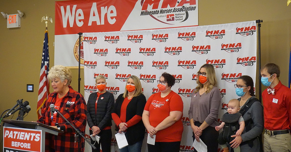 Group of nurses stand in front of podium with Minnesota Nurses Association logos behind them.