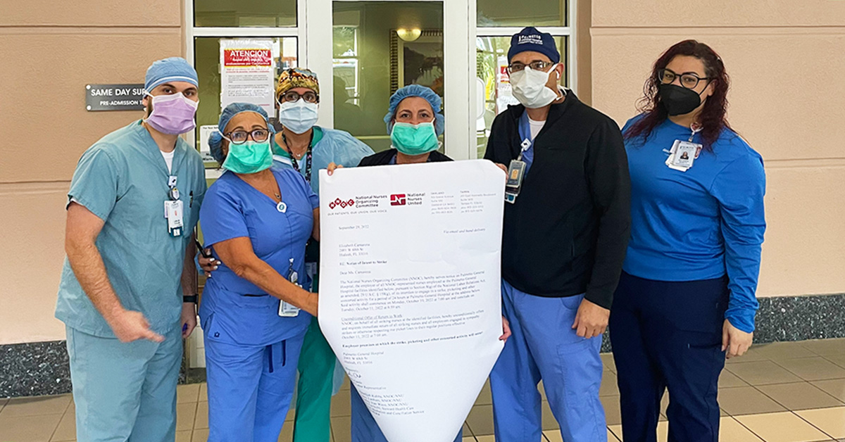 Group of five nurses in front of hospital holding lettter