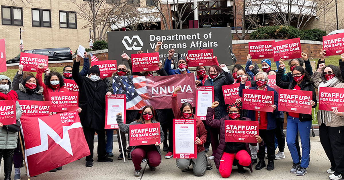 Large group of nurses outside hospital hold signs "Staff Up for Safe Care"