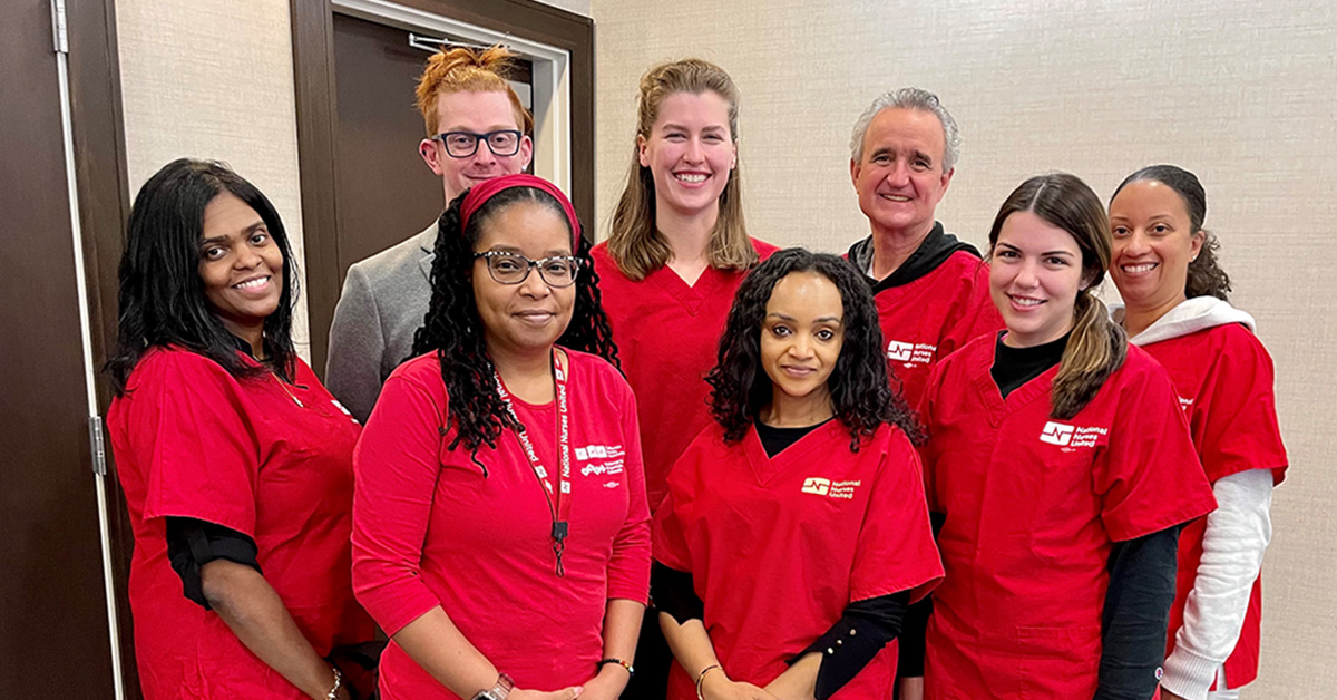 Group of eight nurses in red scrubs smiling