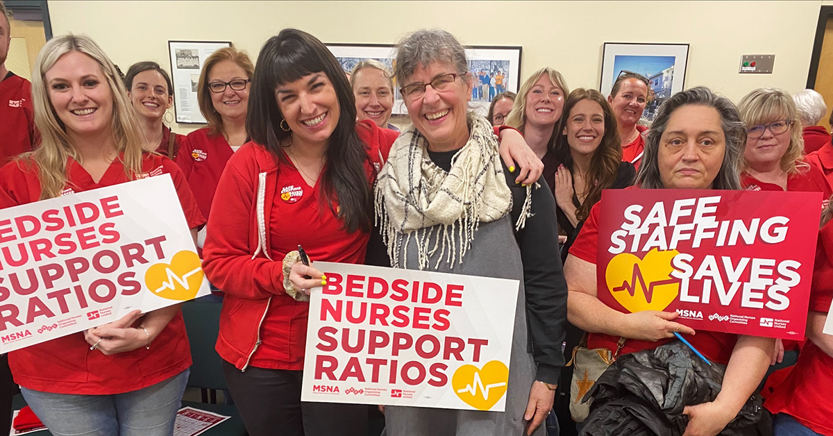 Group of nurses stand at podium smiling and holding signs "Bedside Nurses Support Ratios"