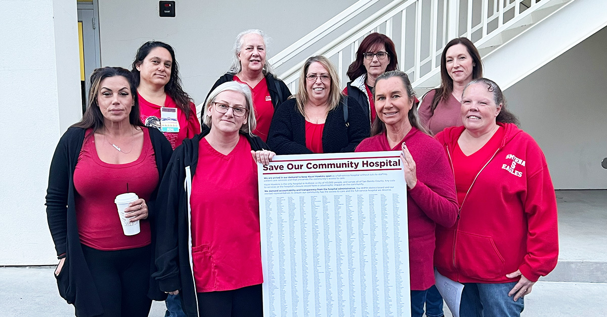 Large group of nurses hold long list of petition signatures