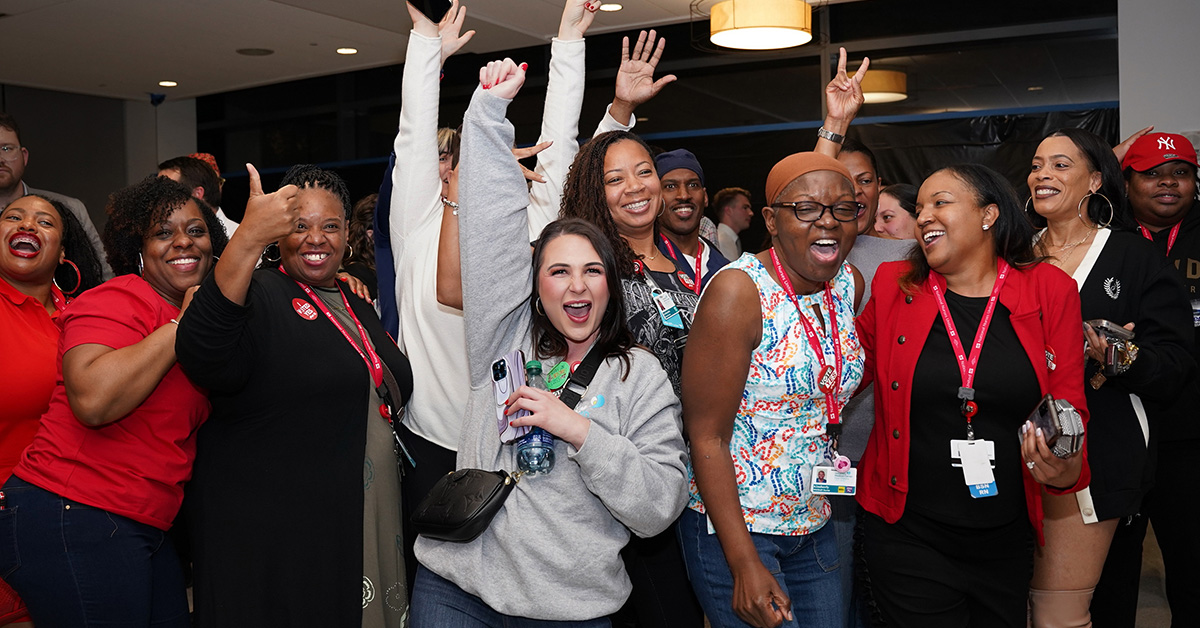 Large group of nurses celebrating with hands in the air