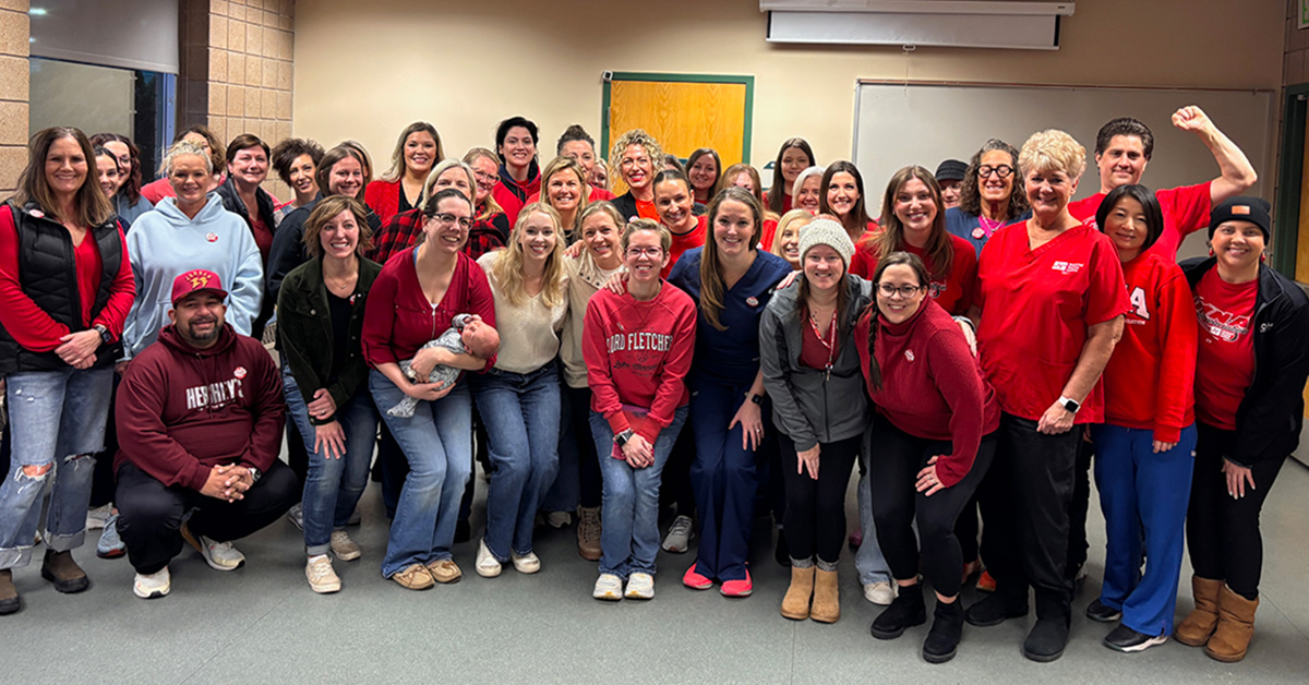 Large group of nurses inside, standing side-by-side, smiling