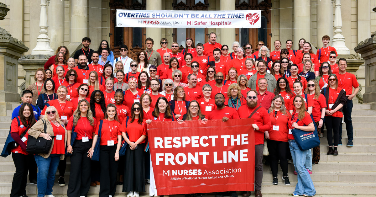Large group of nurses on steps behind banner "Respect the Front Line: MI Nurses Association