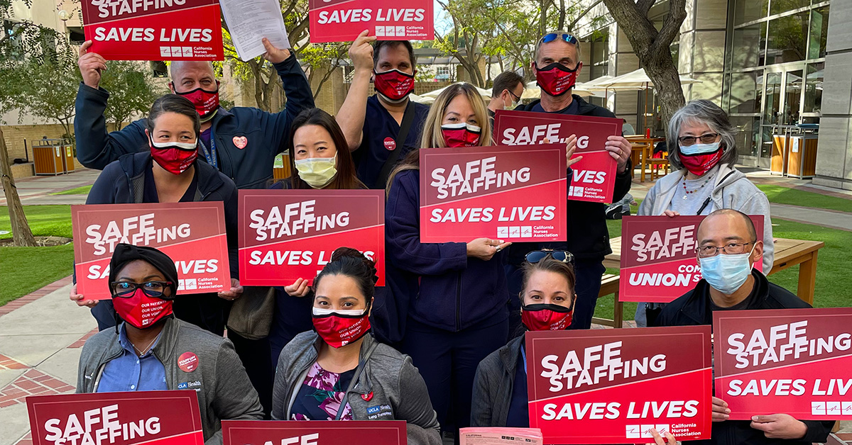 Large group of nurses holding signs "Safe Staffing Saves Lives"