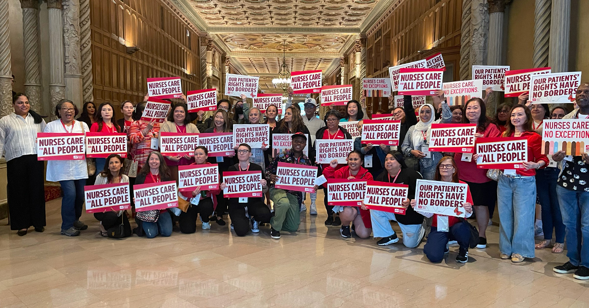 Large group of nurses inside, holding signs "Nurses care for all people"