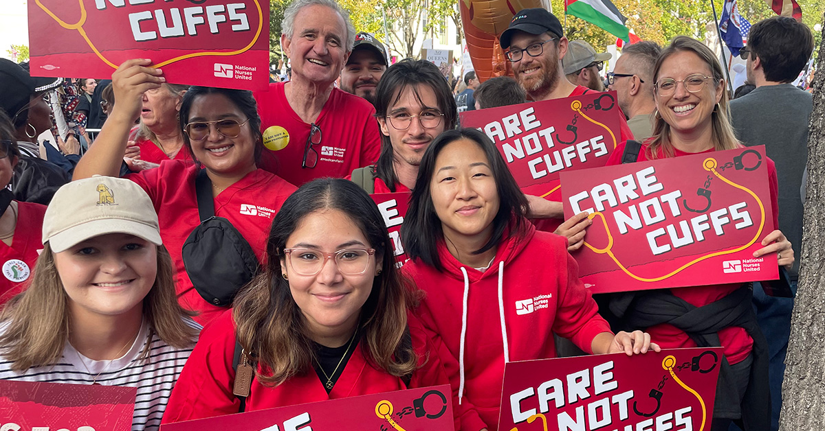 Group of nurses smiling, holding signs "Care Not Cuffs"