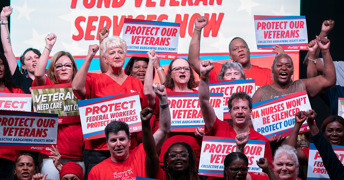 Large group of nurses holding signs "Protect Our Veterans"