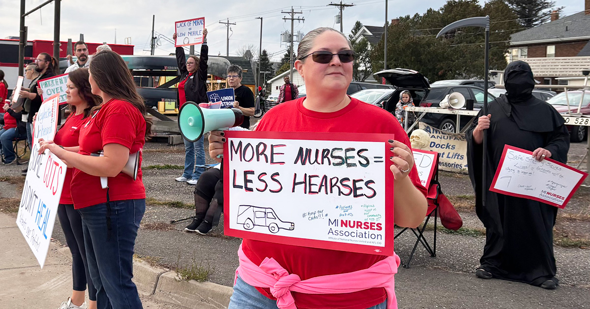 Nurse outside holding sign "More Nurses = Less Hearses"