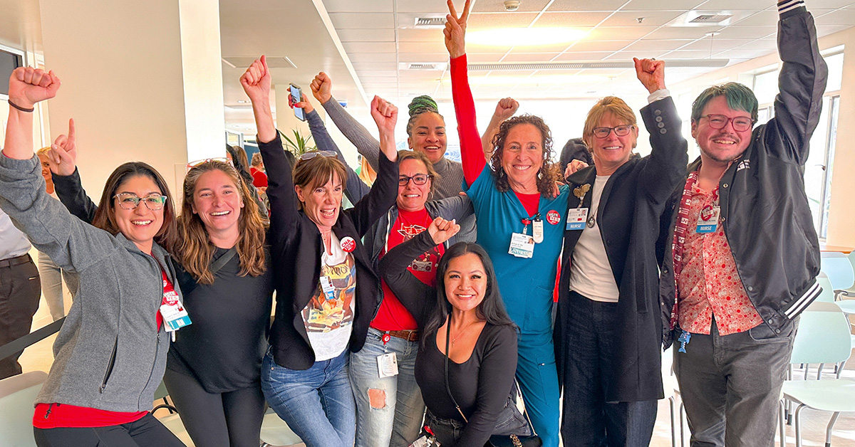 Group of nurses inside, smiling, celebrating, with hands in air