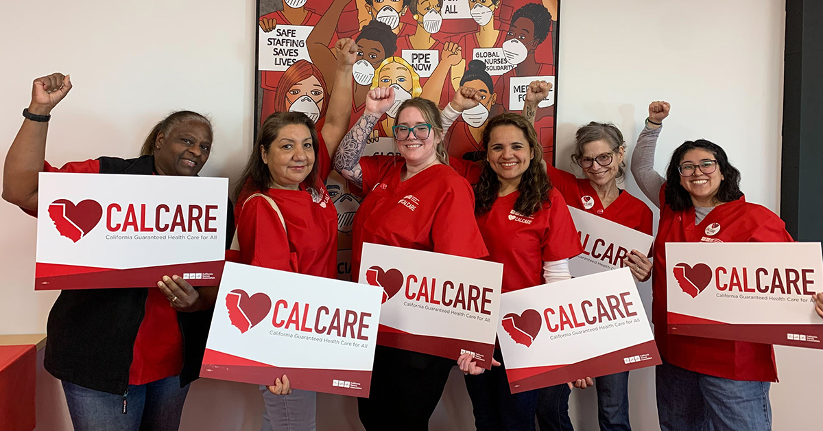 Group of five nurses smiling, holding CalCare signs, with raised fists