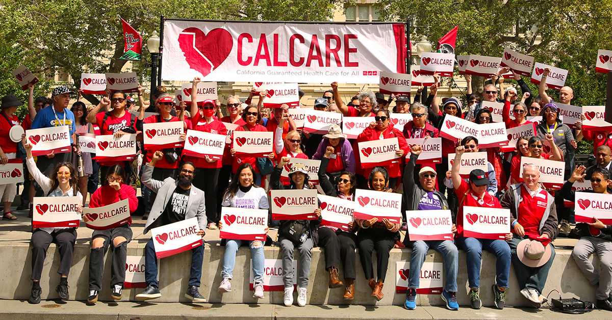 Large group of people outisde, holding CalCare signs and banner