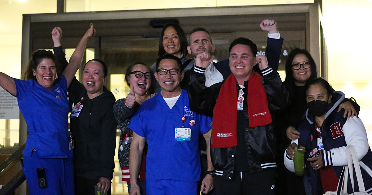 Group of nurses outside hospital celebration union election win, smiling, hands in the air