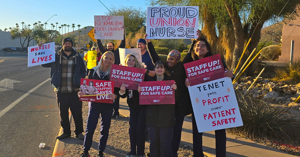 Nurses picketing on side of the road, some hold signs "Safe Staffing Saves Lives"