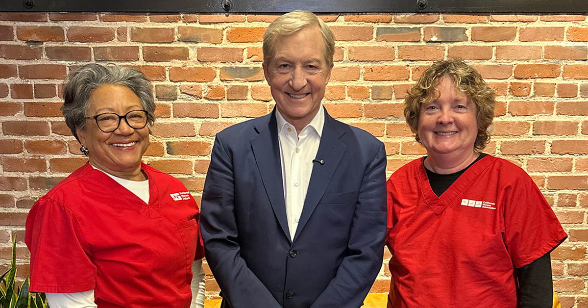 Two nurse leaders posing, smiling with Tom Steyer