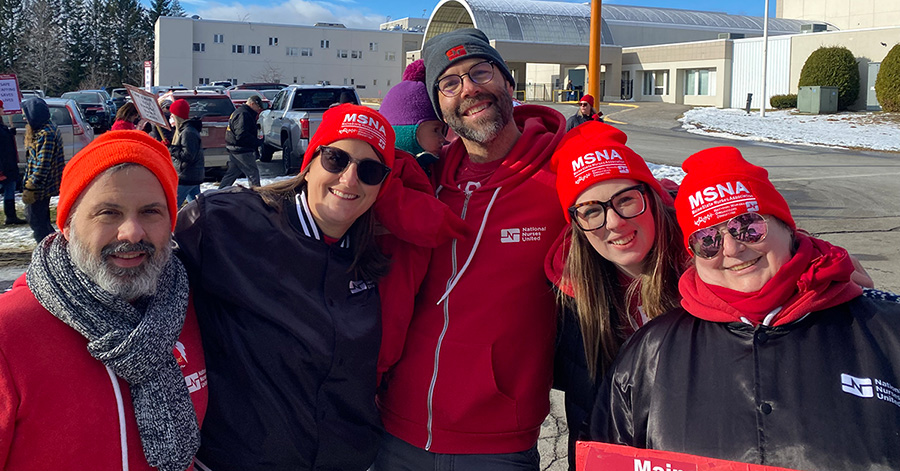 Five nurses outside hospital in cold weather clothes, smiling