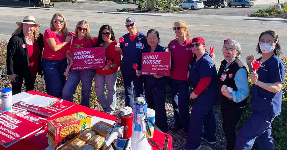 Large group of nurses outside, picketing, with signs "Union nurses build healthy communities" 