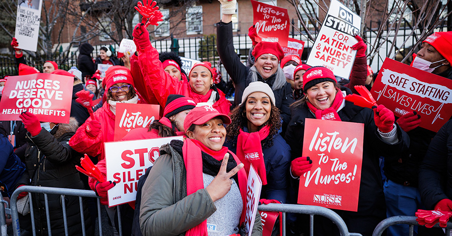 Group of nurses on strike line, smiling, holding signs "Listent to the Nurses"