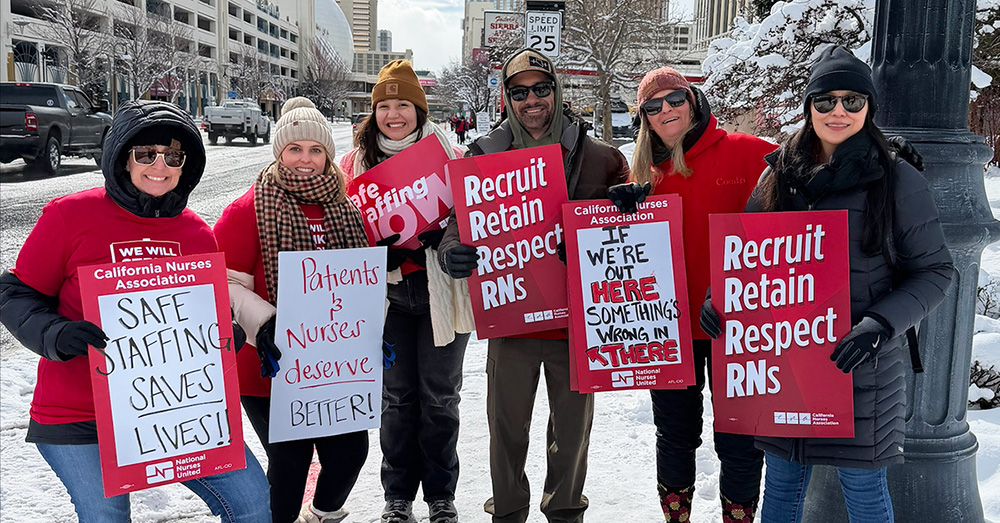 Group of nurses outside in cold weather clothes holding signs "Recruit, Retain, Respect RNs" and "Safe Staffing Saves Lives"