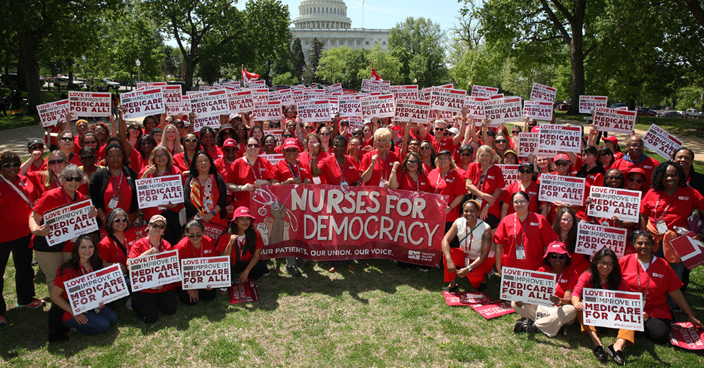 Large group of nurses in Washington D.C., holding signs "Medicare for All" and banner "Nurses for Democracy"