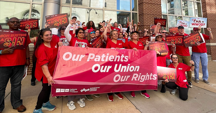 Group of nurses outside, holding banner "Our Patients, Our Union, Our Rights" and signs "Union Busting is a Sin"