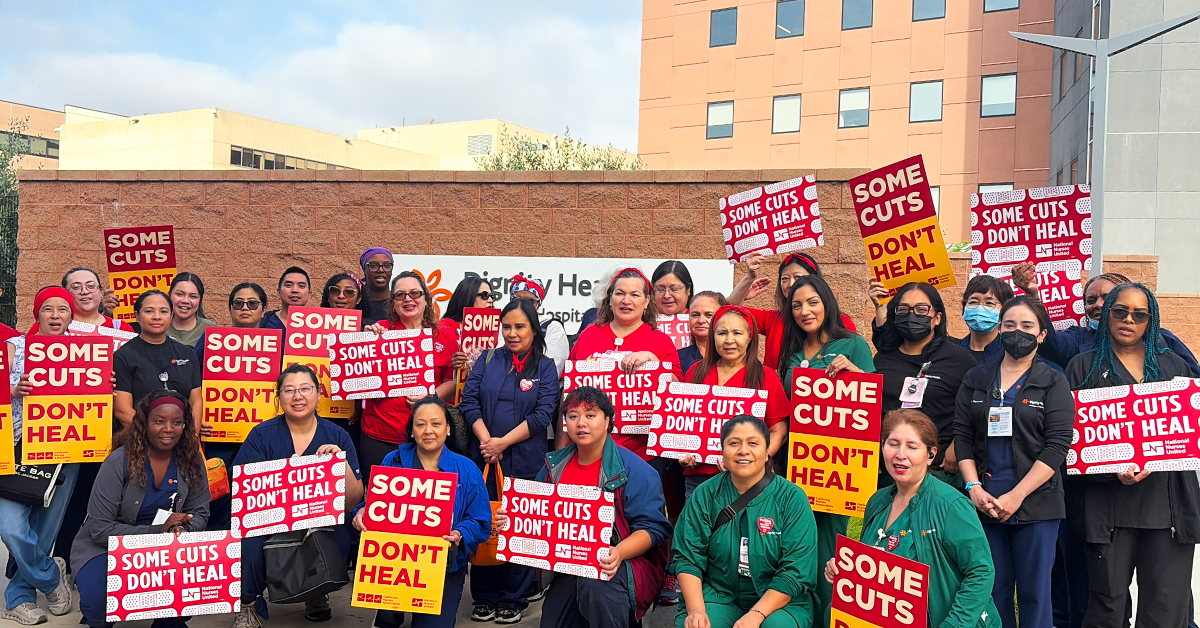 Group of CommonSpirit nurses with signs "Some Cuts Don't Heal"