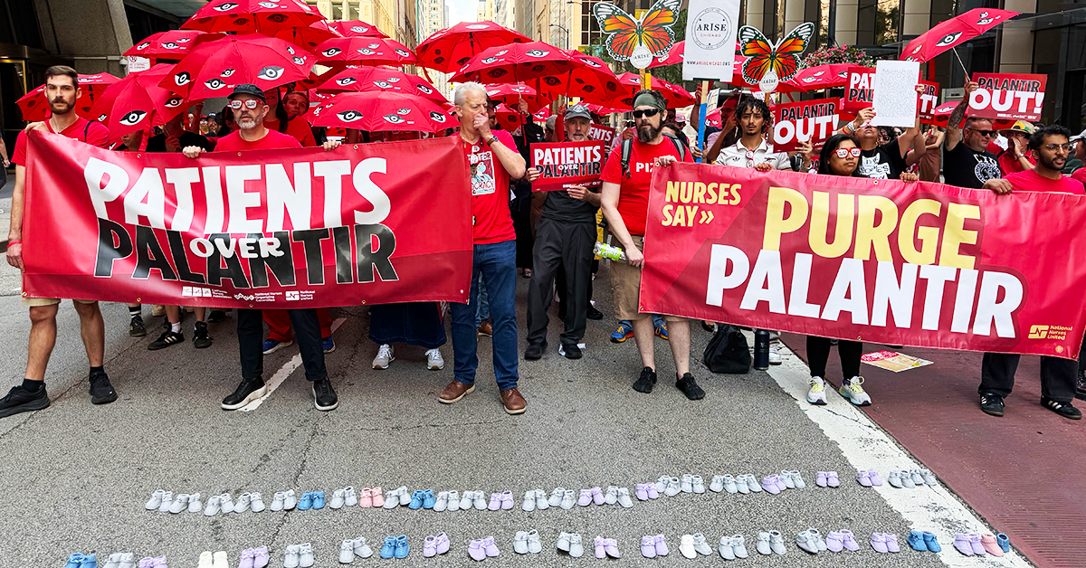 Nurses in streets holding 'Purge Palantir' banners, umbrellas, in front of baby shoes