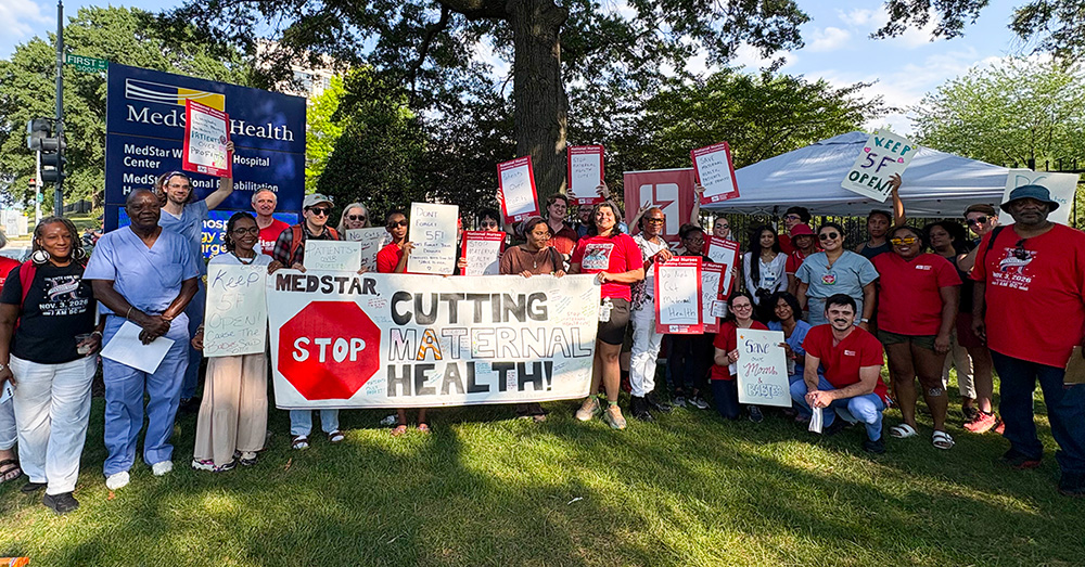 Large group of nurses and community outside hospital, holding signs and banner "MedStar: Stop Cutting Maternal Health"