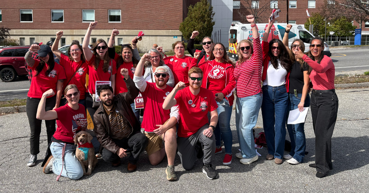 Group of nurses outside hospital, smiling, with raised fists
