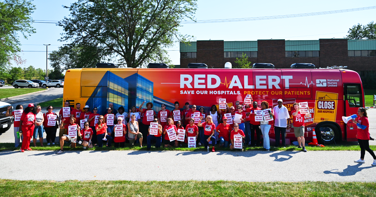 Nurses at Olympa Fields in front of Red Alert Tour bus with signs "Prime RNs United for Our Patients"