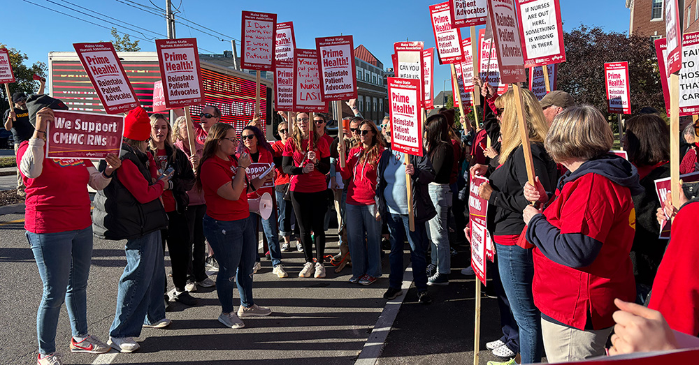 Large group of nurses rallying holding signs "Prime Health: Reinstate Patient Advocates"