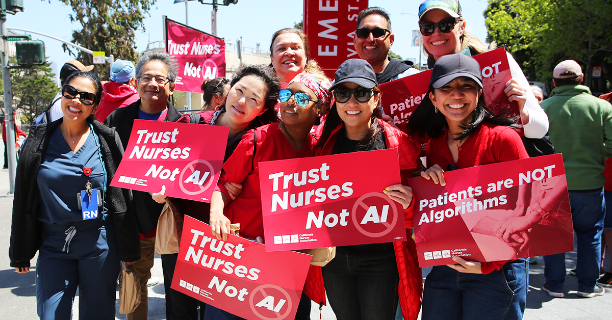 Group of nurses holding signs "Trust Nurses Not A.I." and "Patients are NOT algorithms"