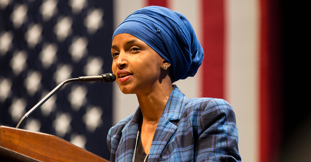 Rep. Ilhan Omar at podium in front of American flag