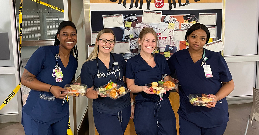 Four nurses in blue scrubs smiling