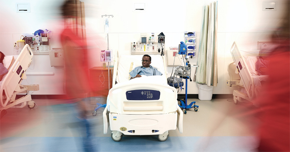 Child in hospital bed being passed by hospital staff